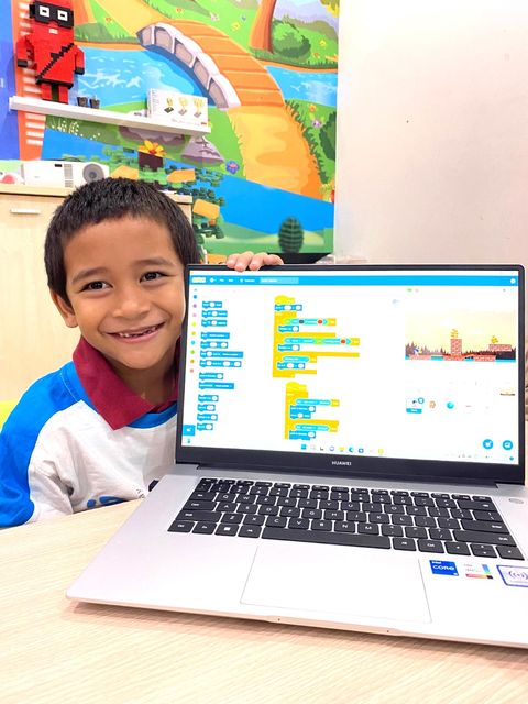 A young student showing the block-coding project on his laptop